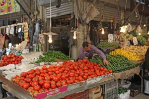 Merchant sets up one of the multitude of produce stalls at Amman Souk