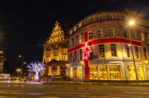 The West End of Princes Street is festively lit with a red ribbon bow around the building