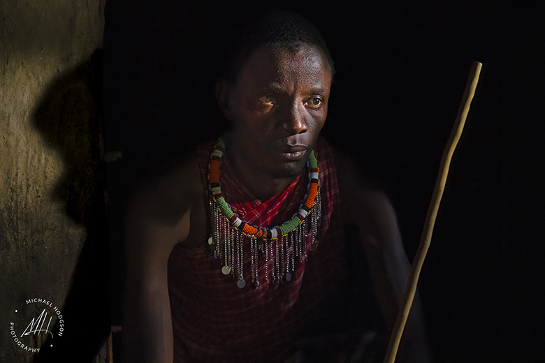 Masai warrior sitting in shadows and light