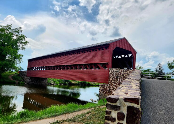 Red covered bridge, with a rock foundation, spans Marsh Creek near Gettysburg.