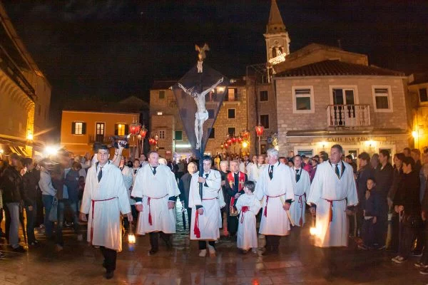 People in white robes are marching on the Island of Hvar. One person is carrying a cross.