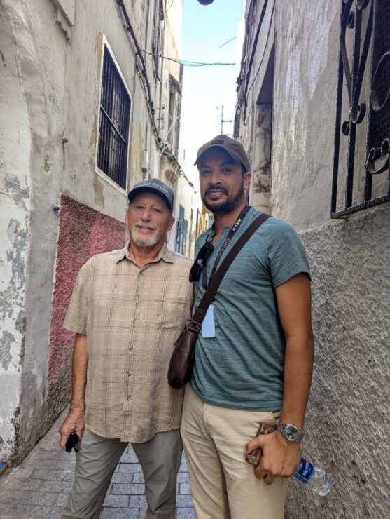 American and Moroccan men stading together in a narrow street. 