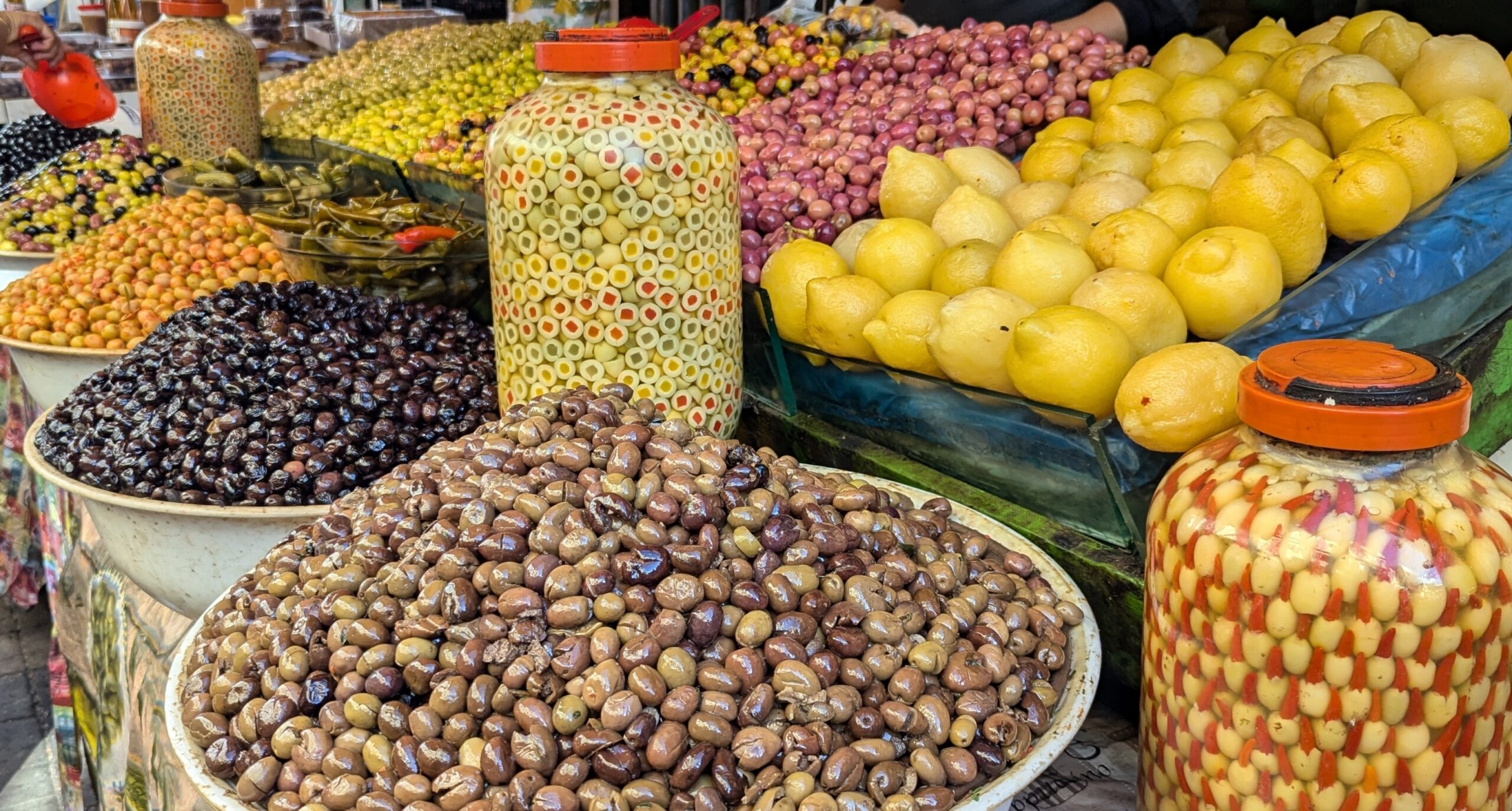 Olives in bowls and large glass jars and lemons displayed at an open air market in Tangier, Morocco.