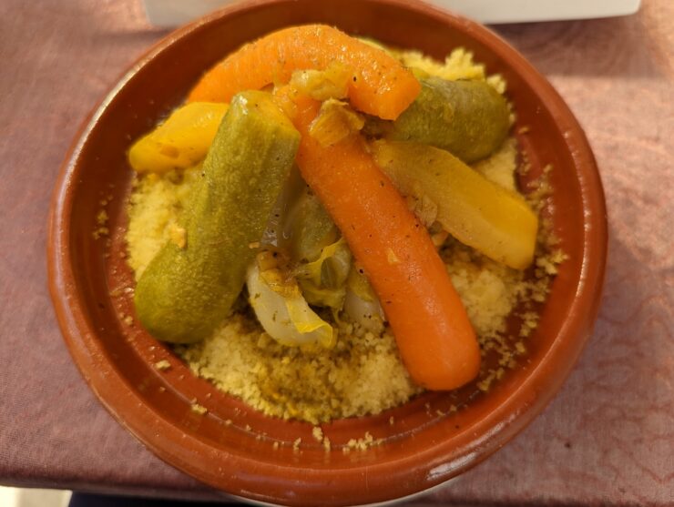 Strips of carrot and squash laid over a mount of couscous in a pottery base.
