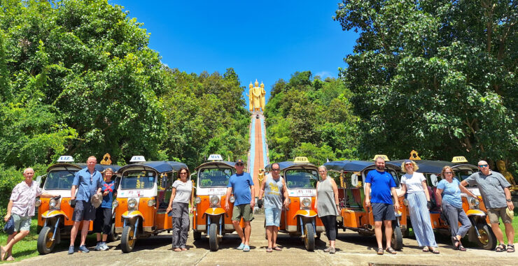 Tuk Tuks and occupants lined up in row front of grand stairs and Buddha statues