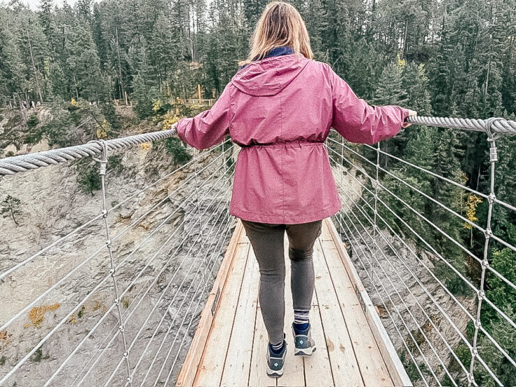 Woman in pink coat walking on a suspension bridge