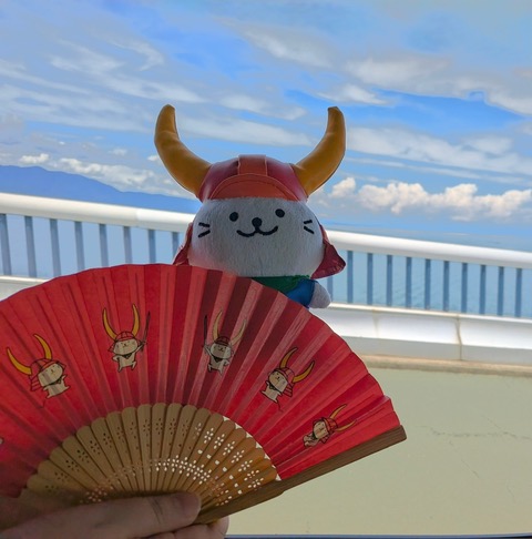 Hikonyan, the official mascot of Hikone City, with Lake Biwa in the background
