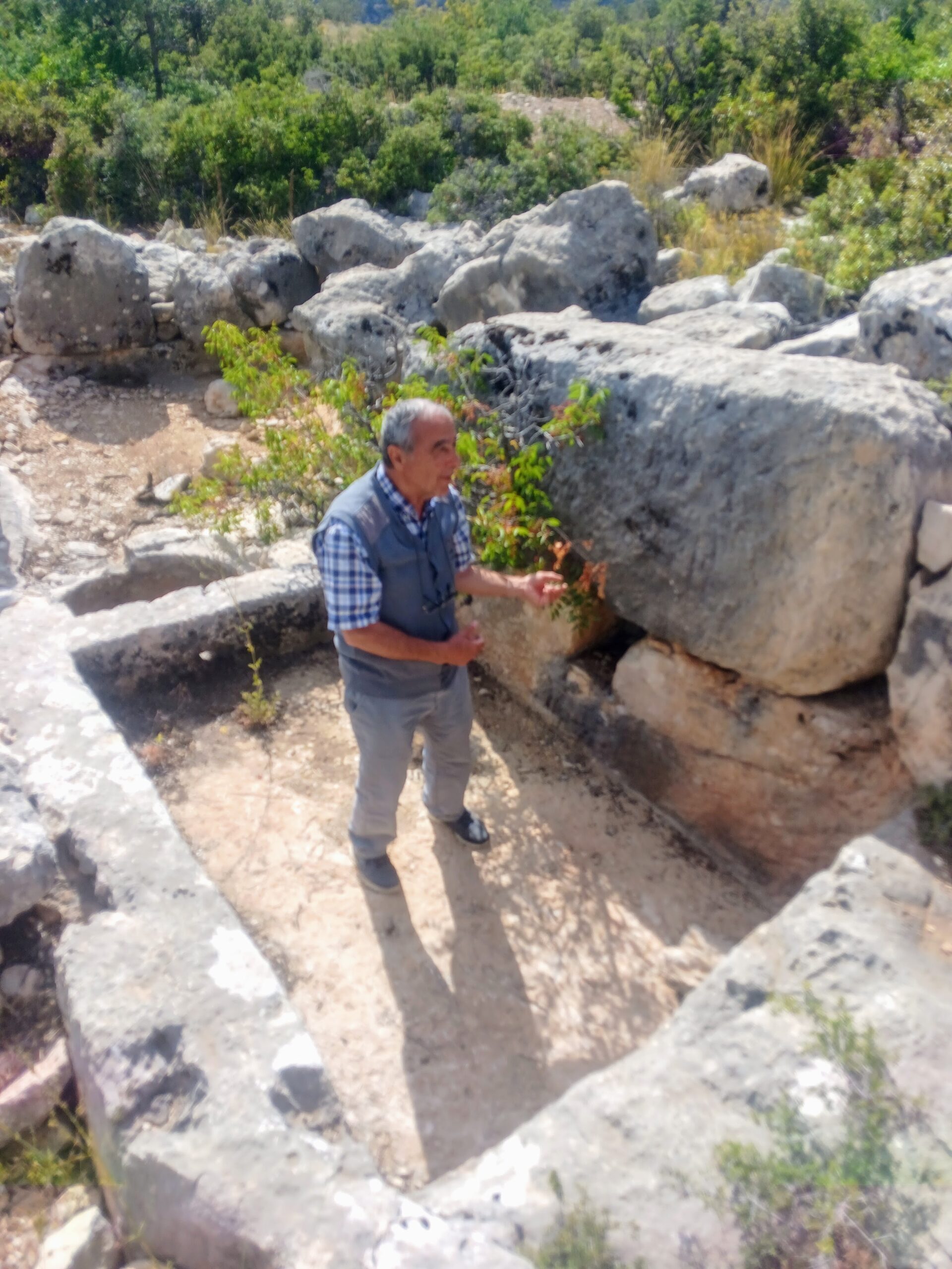 Elderly man standing in an ancient wine press carved into the limestone rock of the Taurus Mts, Turkey