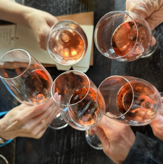 Hand with glasses filled with rosé wine in a toast.