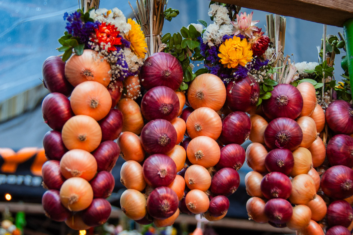 Red and yellow onions, tied together in strands and topped with ribbons and flowers.
