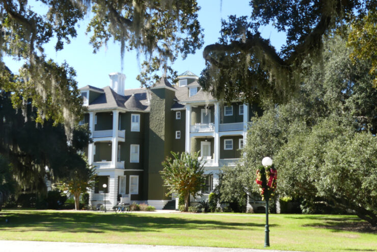 Green three story building with white balconies.