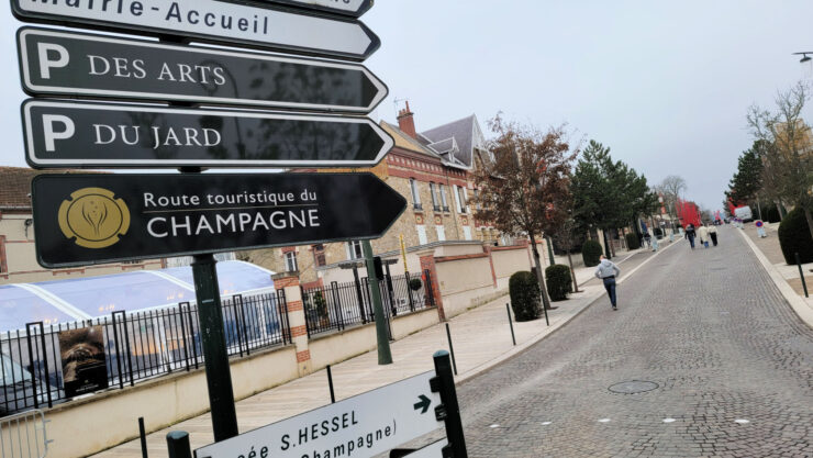 close-up of sign reading "Route touristique du Champagne and a long boulevard in the background during Habits de Lumière Epernay