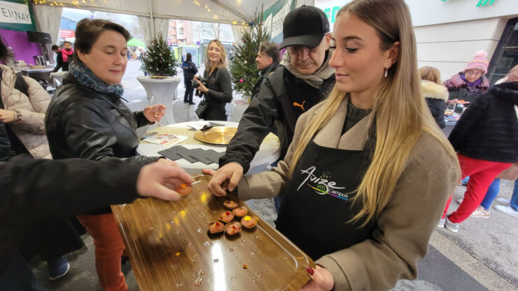 Young woman holds try of appetizers at Habits de Lumière Epernay culinary event