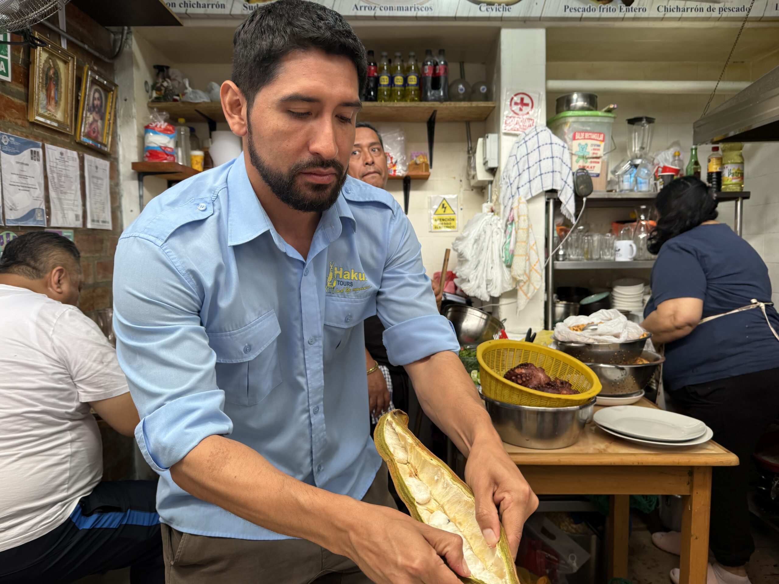 Guide Cesar Contreras shows the sweet pulp-encased seeds inside a yellow-green pod of the pacay fruit during a tour of Mercardo No. 2 in Lima. ©Linda Barnard