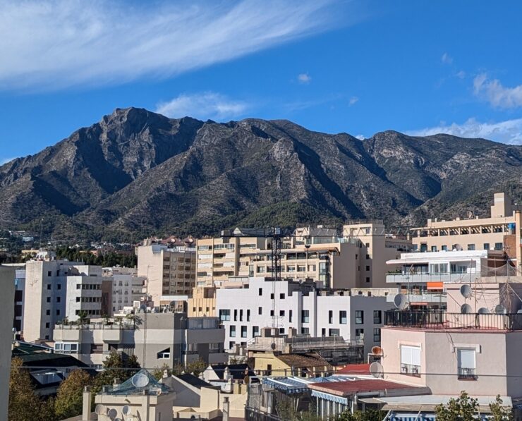 A craggy hillside fronted with dense modern urban buildings