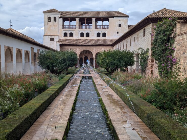 A long shallow canal with a series of arched fountains. Narrow gardens are planted on either side.
