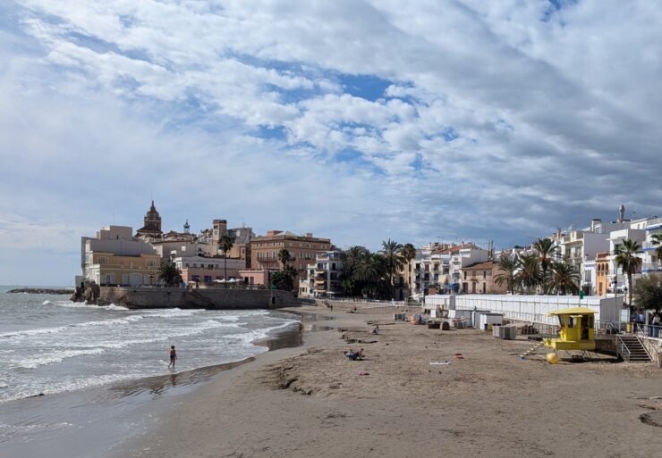 A broad expanse of sand with the sea to the left and a dense collection of old buildings where the land meets the sea