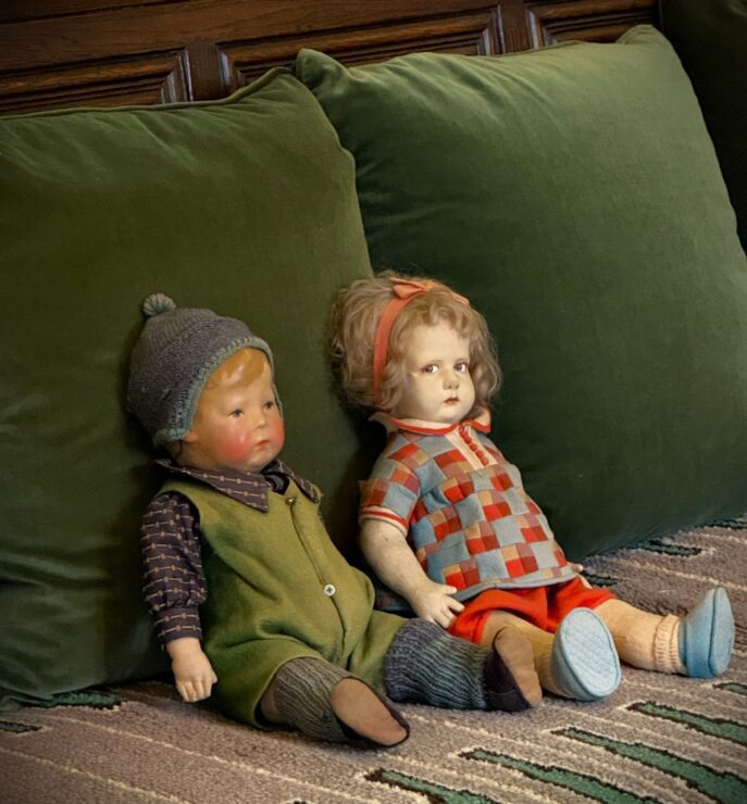 This photo shows the close up of the very realistic dolls on the sofa in the family area where one of the dolls is offering a side eye.