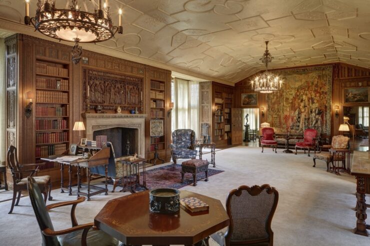 This photo shows the huge library inside Cranbrook House, with period furnishings, a fireplace, and tapestry.