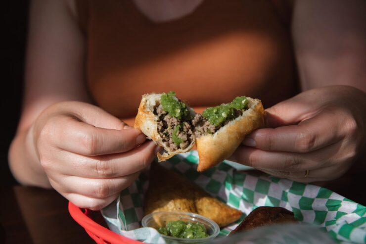 A customer in Afro Deli in Minneapolis opens a sambusa, similar to an Indian samosa