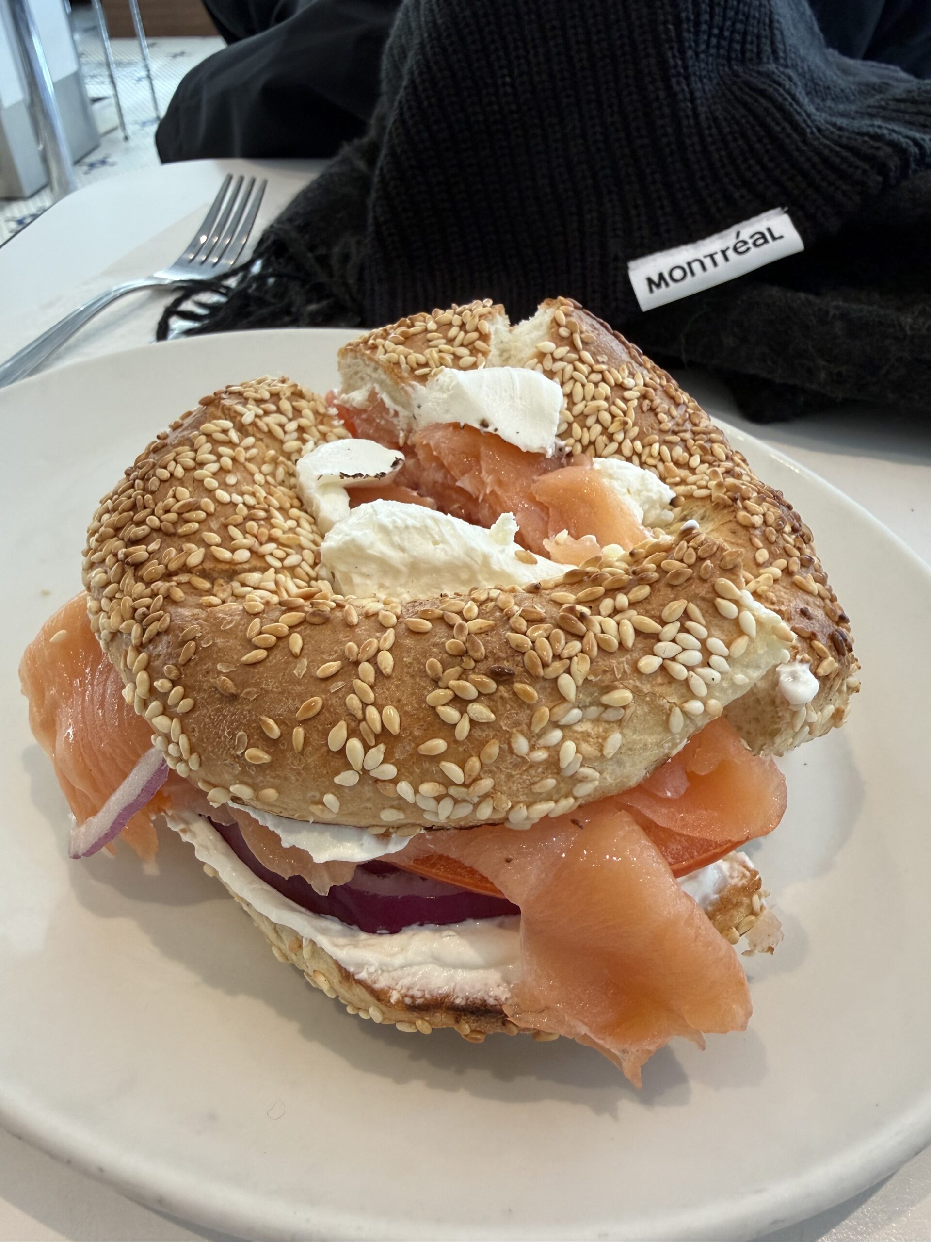 A bagel filled with cream cheese, smoked salmon, onion and tomato.