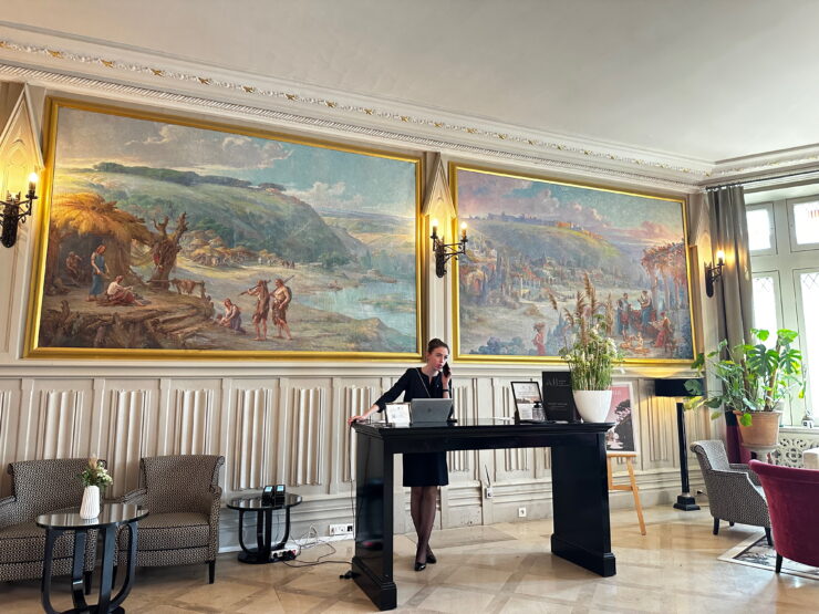 hotel lobby with woman standing at desk and paintings on the wall