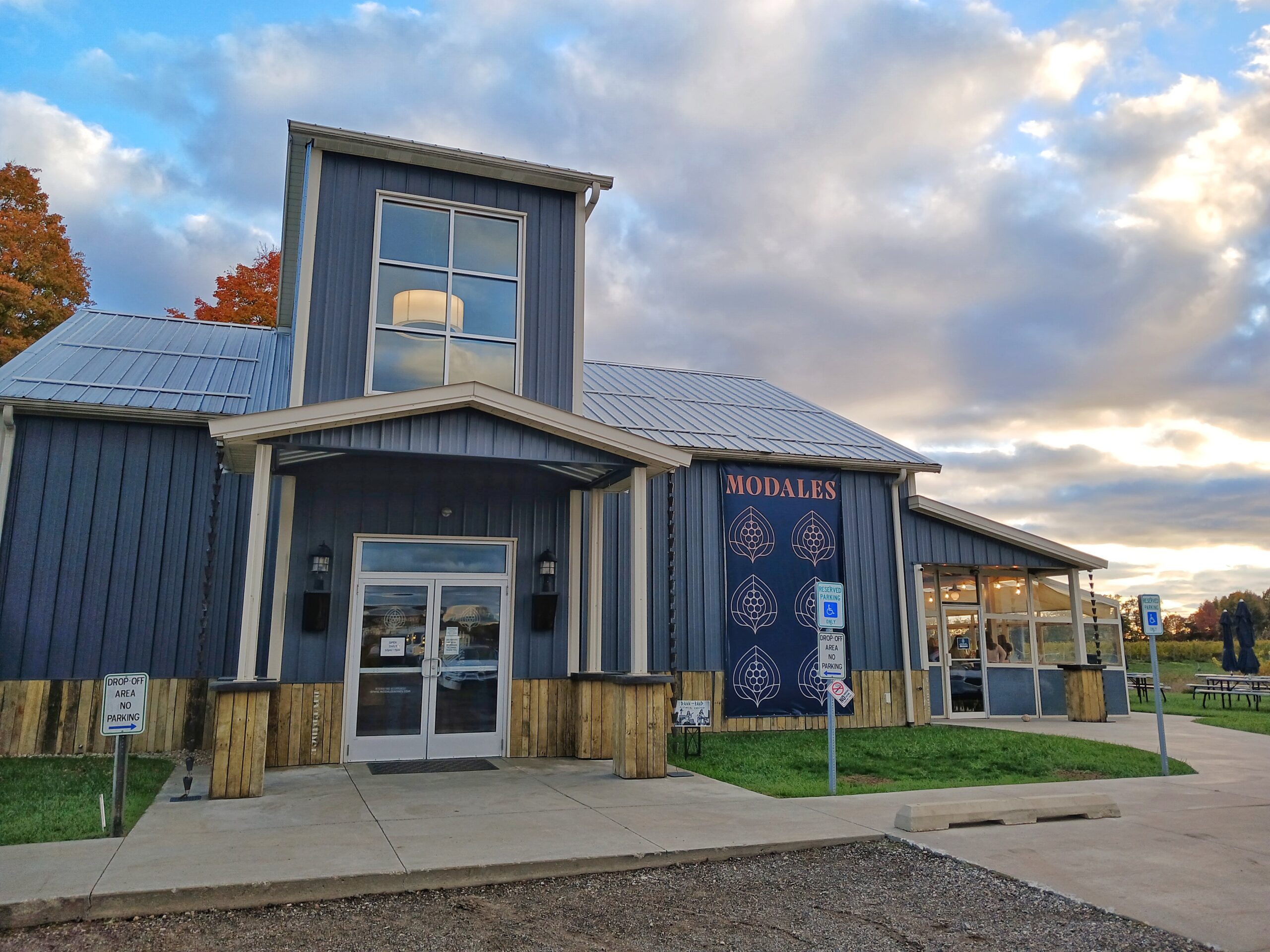 Light blue metal, farmhouse-style building under a cloud-filled blue sky