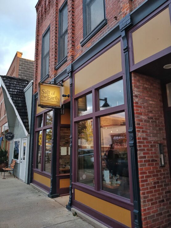 Warm brick and glass building with old-fashioned sign hanging above the door