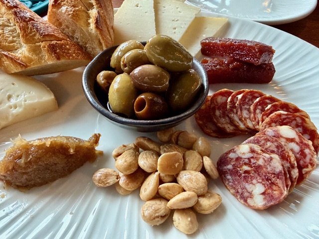 A charcuterie plate with sausage, olives, almonds, Spanish cheese, quince, and fennel jam.
