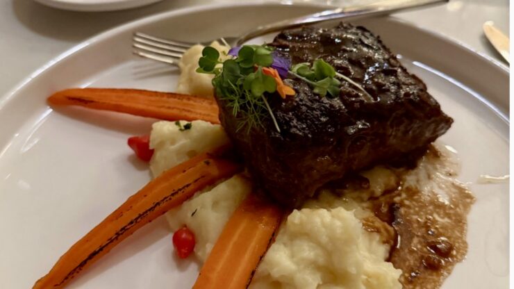 Bourbon-braised short rib plated with vegetables and garnish at Mission Resort + Club in Howey-in-the-Hills, Florida.