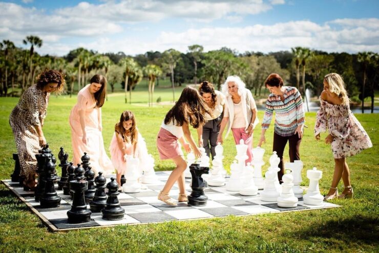 Guests playing outdoor chess on the lawn at Mission Resort + Club, with resort landscaping and palm trees in the background.