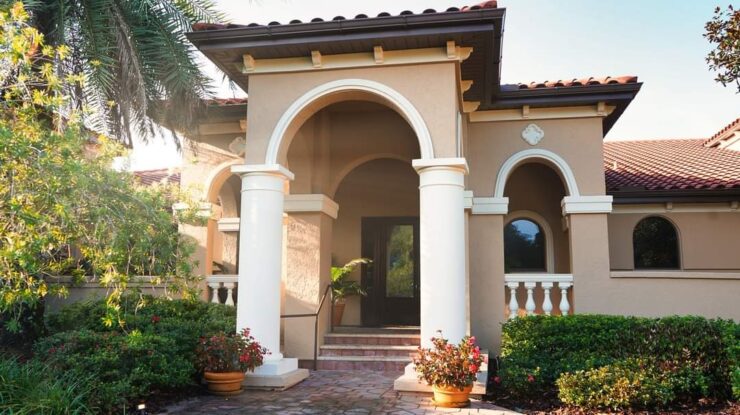 Entrance to The Spa at Mission Resort + Club, featuring arched Mediterranean-style architecture, columns, greenery, and a shaded walkway.
