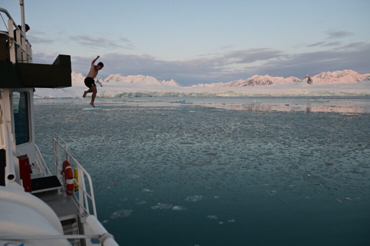 A man jumps from the upper decks of a boat into the ice cold water of a fjord in Svalbard.