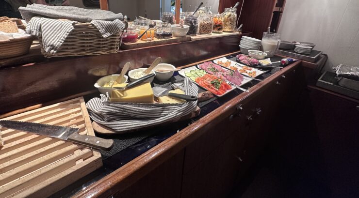 Trays of cheeses, meats, fruit and other finger-foods are presented on shelves.