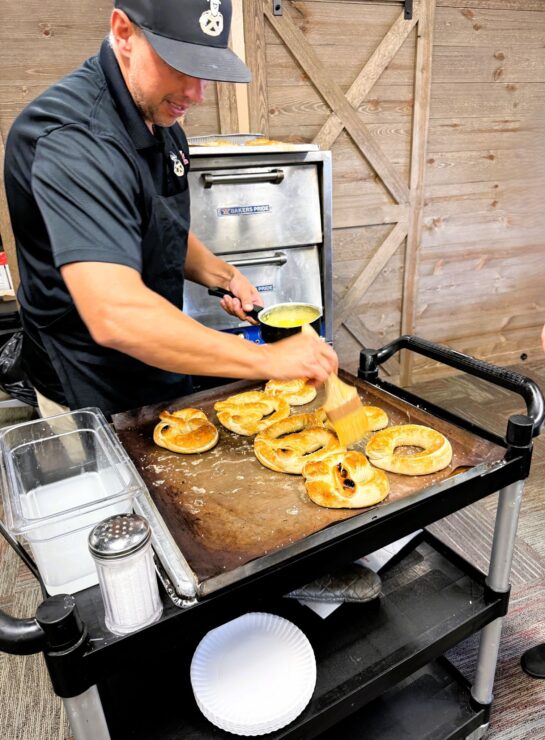 Ben Miller of Ben's Soft Pretzels butters some freshly baked pretzels.