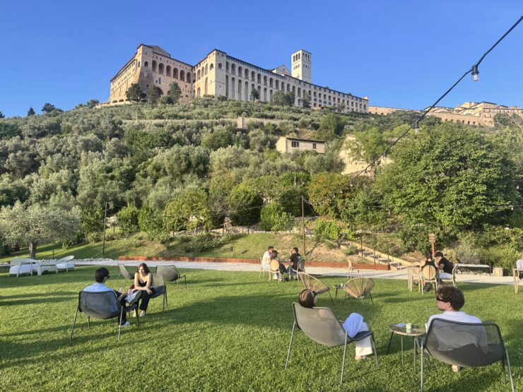 People sit round tables on a lawn with a cathedral overlooking them