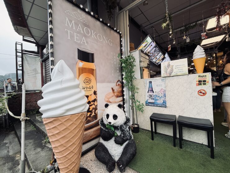 Tea shop with displays of soft serve tea ice cream cones and a panda statute nibbling on tea leaves.