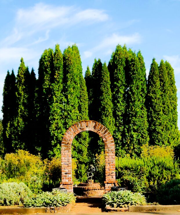 Arched brick entrance to Joel Palmer House's garden, with a statue in the center.