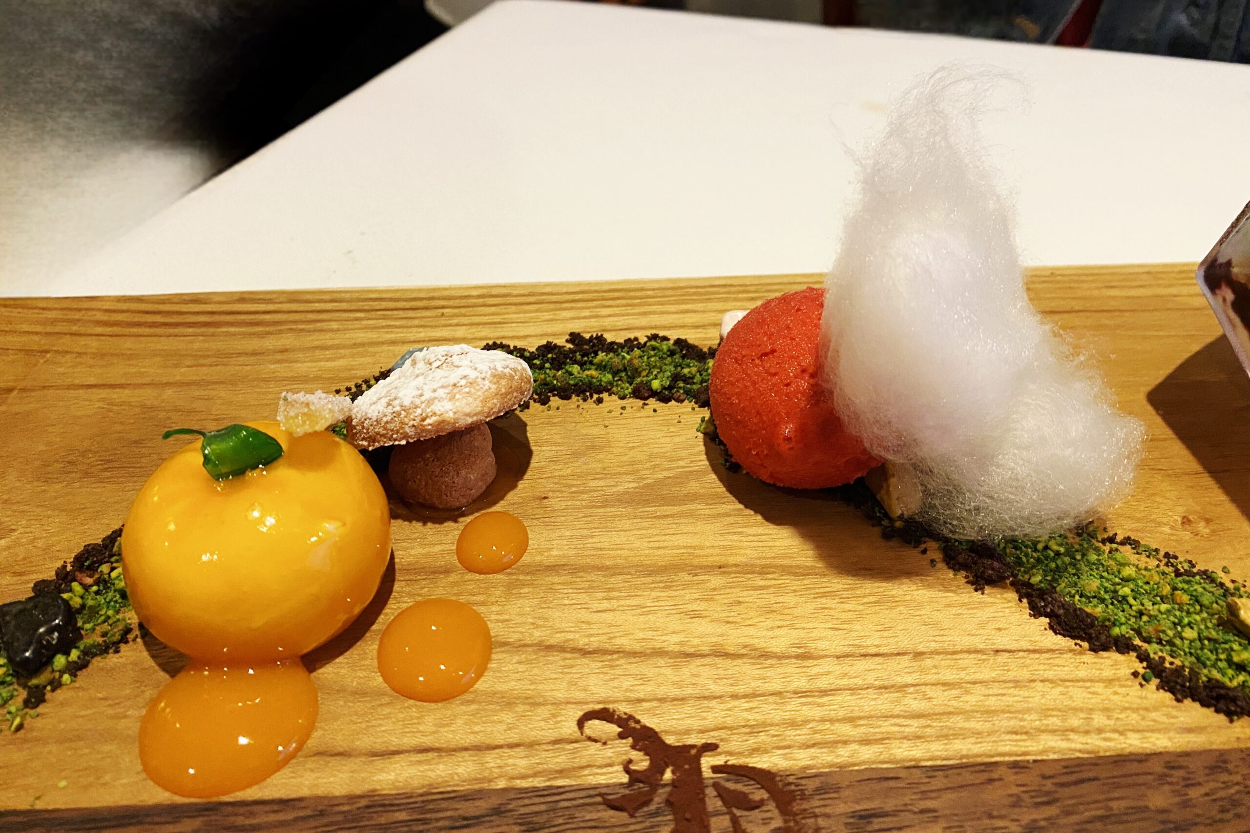 A small treat on the board that appears to be a pumpkin, and a tuft of cotton candy.