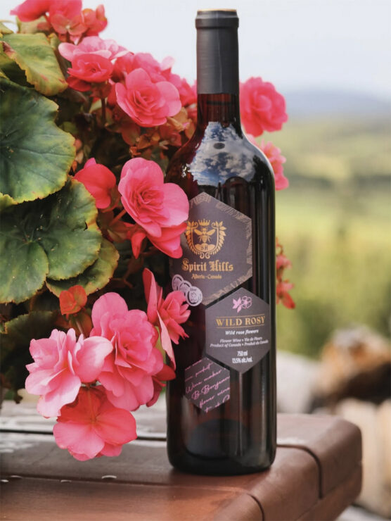 Wild Rosy Flower Wine Bottle with the Alberta Wild Rose Petals surrounding it.