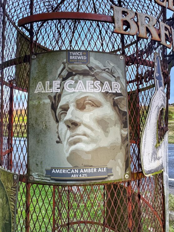Cage with sign reading Ale Caesar and picture of Roman statue