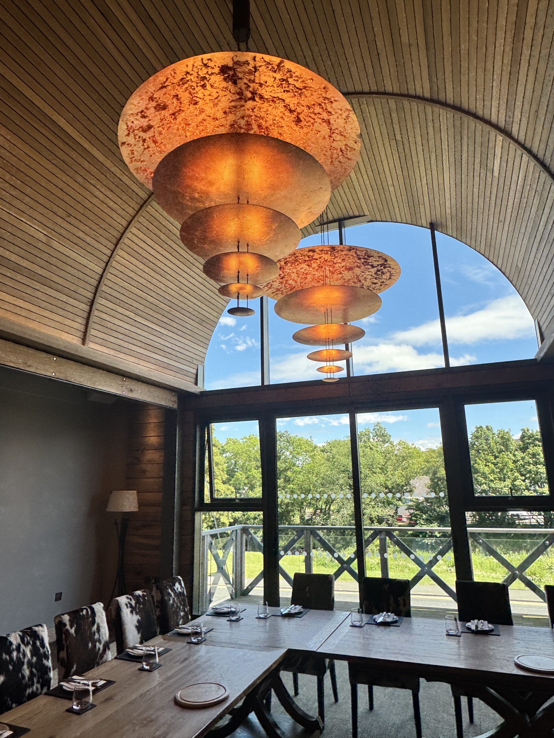 Wooden table with large copper lamps overhead